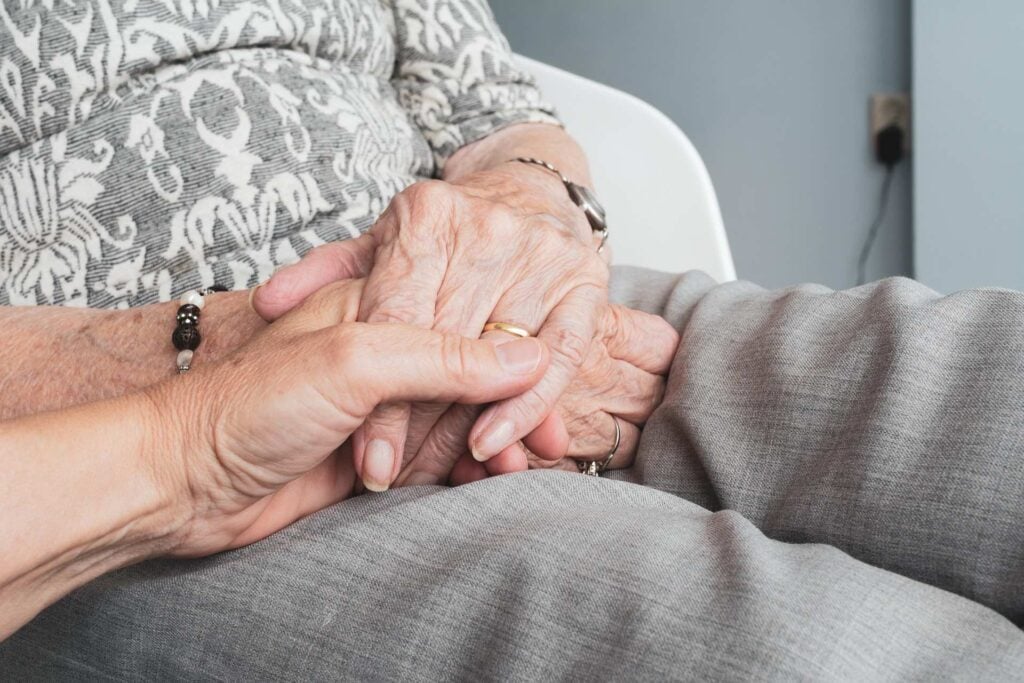 Elderly person holding hands